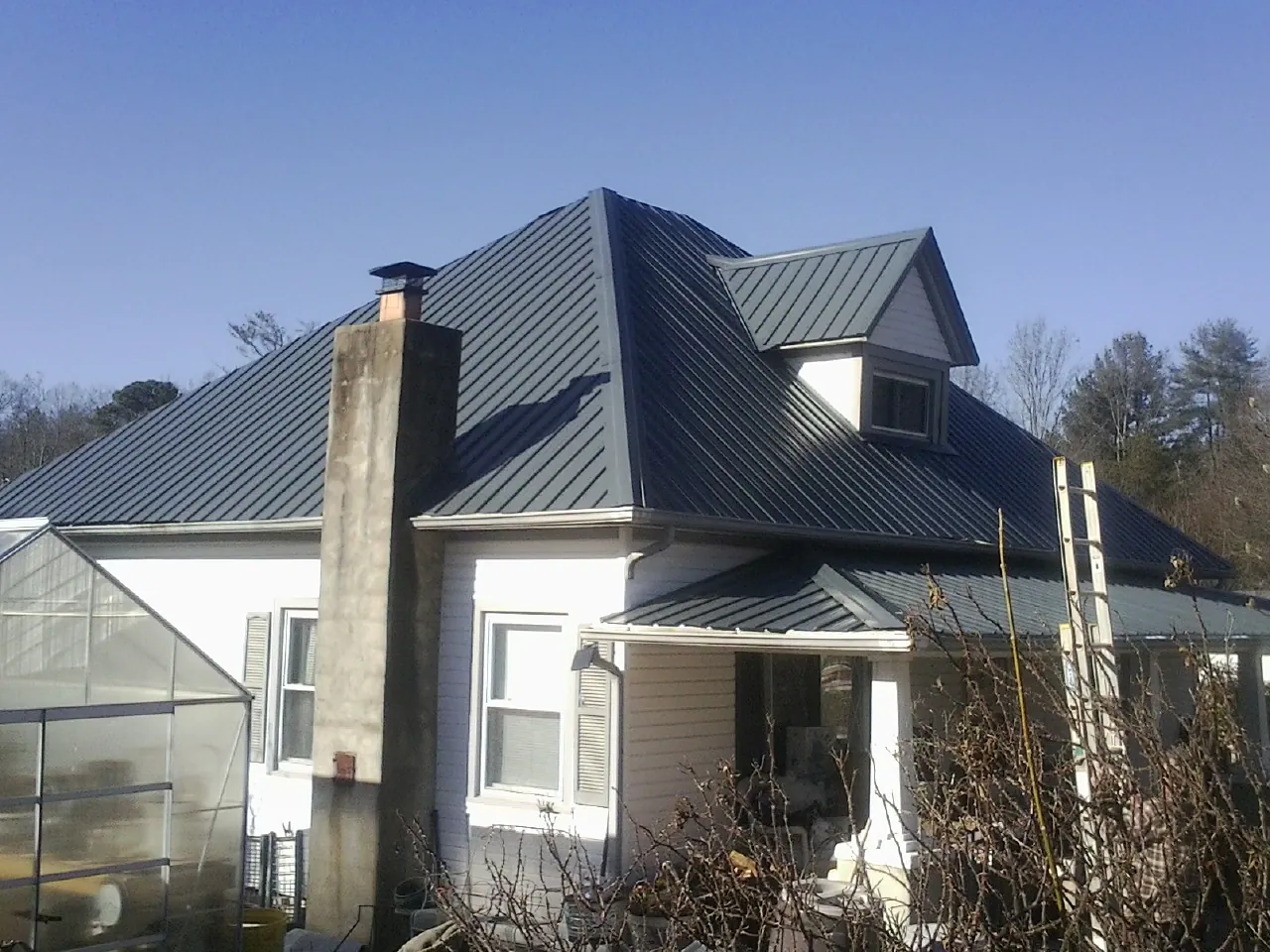 Dark blue standing seam metal roof on a white farmhouse with dormer — Slate & Tile Roof Repair by Roofing Brothers in Sayville