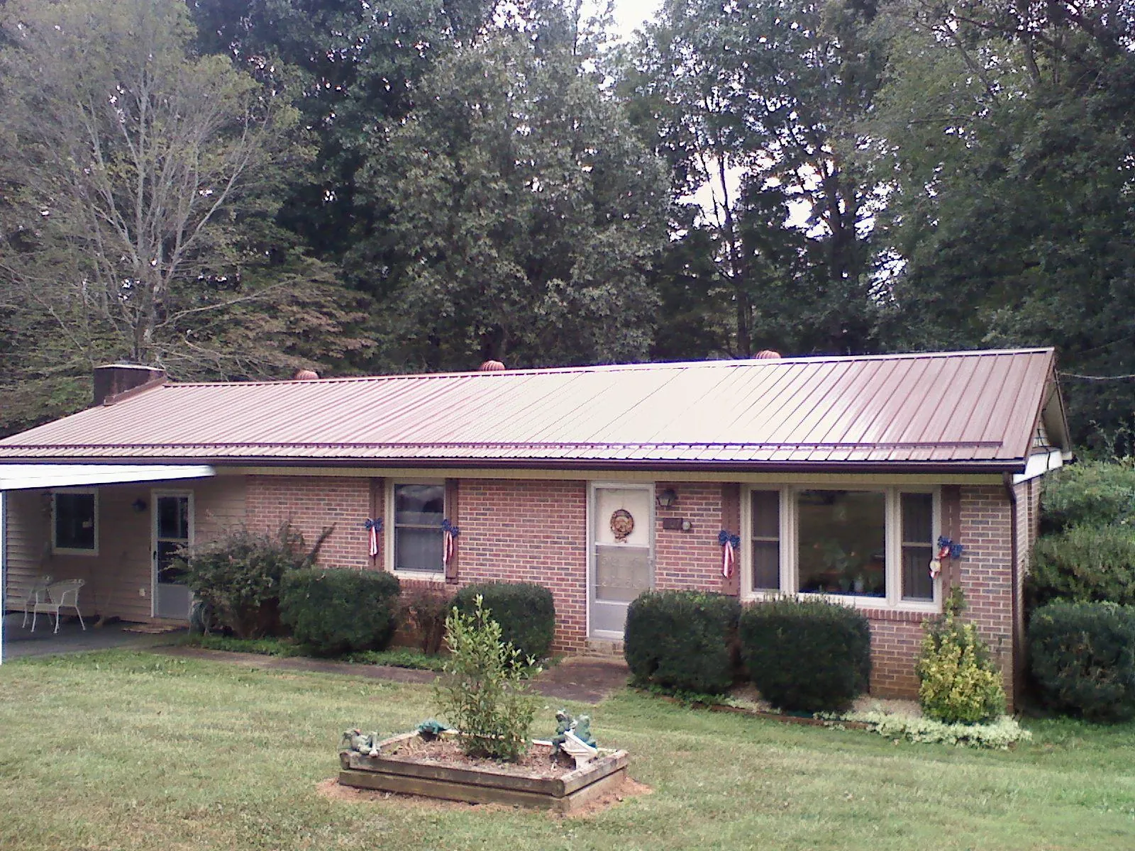 Bronze metal roof on a brick ranch home with a carport in Sayville