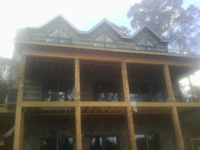 Dormers and porch framing on a large log home under construction — Roof Coating work by our crew in Sayville