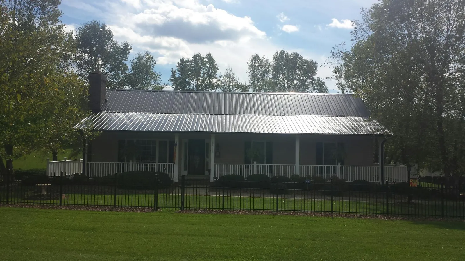 Gray metal roof on a brick ranch with a full width front porch — Gutter Guard Installation work by our crew in Sayville