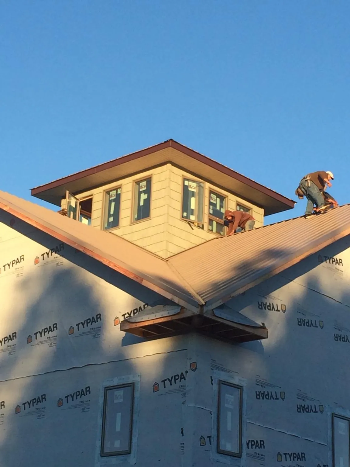 Roofers working around a rooftop cupola on a new metal roof at sunset — Roof Waterproofing in Sayville by Roofing Brothers